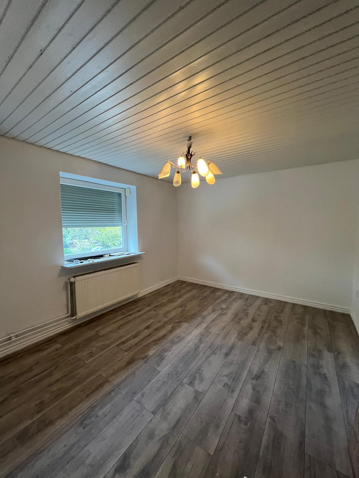 Zimmer mit Holzdecke, Fenster und neuem Bodenbelag